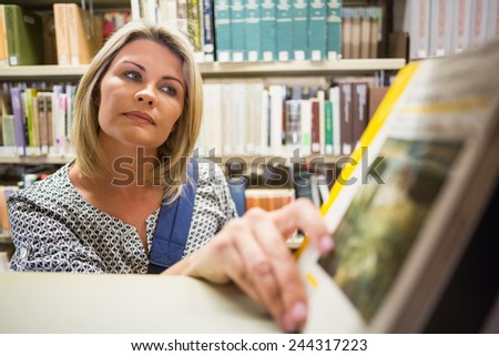 Mature student picking out book in library at the university