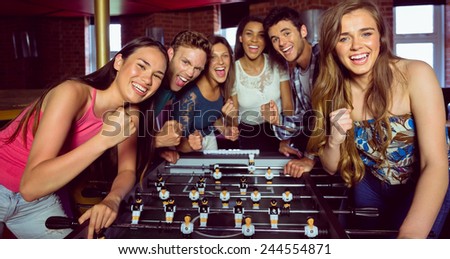 Portrait of happy friends playing table football in a pub