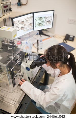 Biochemistry student using large microscope and computer at the university