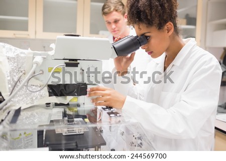 Pretty science student using microscope at the university