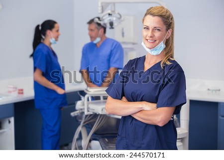 Smiling nurse with arms crossed and co-workers behind her