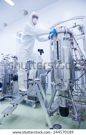 Scientist standing on ladder looking at the camera in the factory