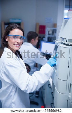 Smiling young chemist using the machine in the laboratory