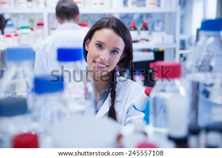 Portrait of a smiling chemist holding a bottle of chemicals in lab