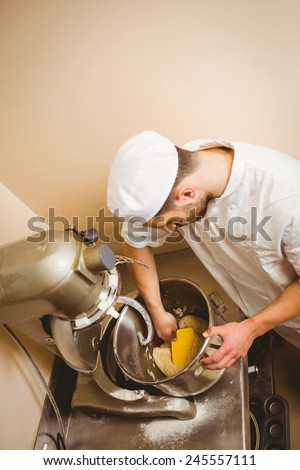 Baker using large mixer to mix dough in a commercial kitchen