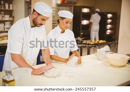 Team of bakers kneading dough in a commercial kitchen