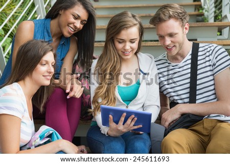 Smiling students sitting on steps with tablet pc at the university