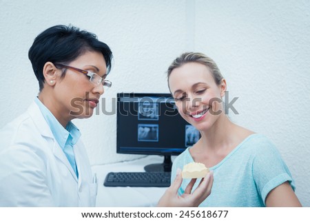 Female dentist showing happy woman prosthesis teeth