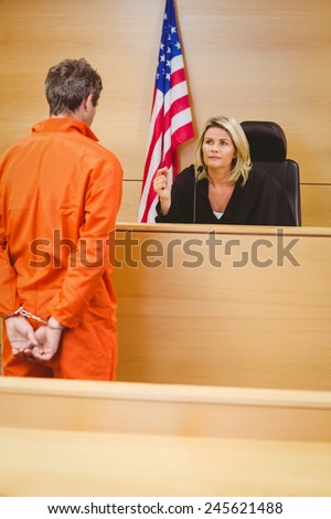 Judge and criminal speaking in front of the american flag in the court room