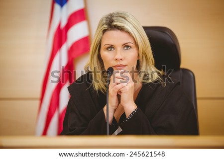 Portrait of a serious judge with american flag behind her in the court room