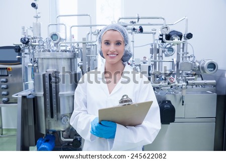 Portrait of a smiling scientist holding a clipboard in the factory
