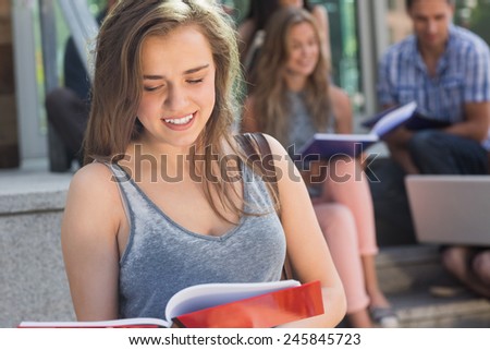 Pretty student reading from notepad at the university