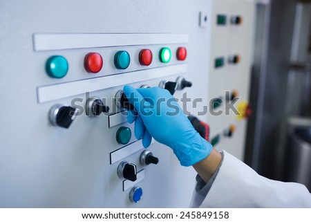 Hand with gloves turning buttons of the machine in the factory
