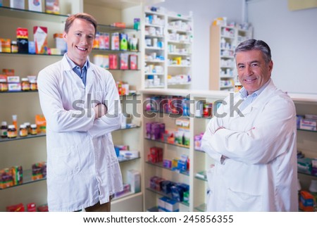 Smiling pharmacists standing with arms crossed in the pharmacy