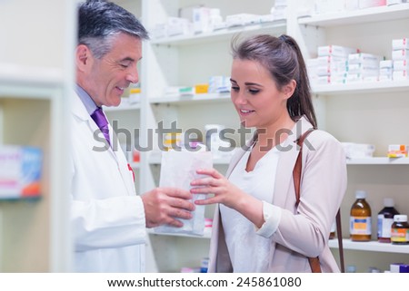 Pharmacist giving paper bag to his customer in the pharmacy