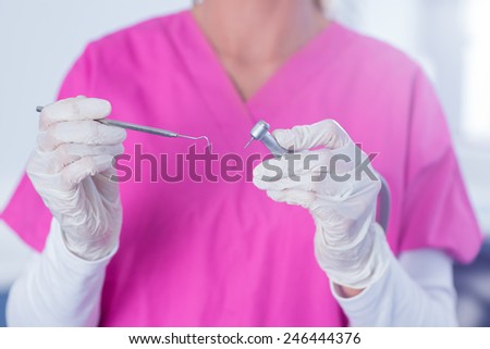 Dentist in pink scrubs holding tool at the dental clinic
