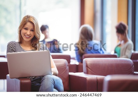 Portrait of a woman using her laptop and smiling at camera at the university