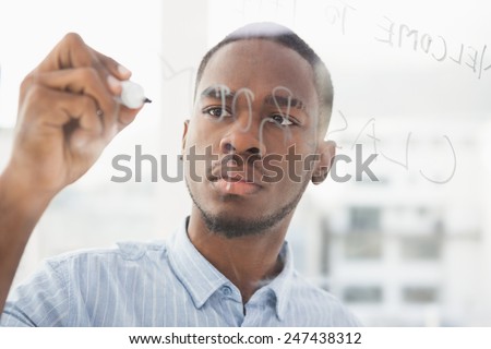 Focused businessman writing on clear board in the office
