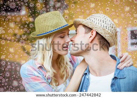 Hip young couple about to kiss against valentines pattern