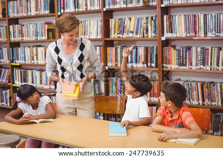 Cute pupils and teacher reading in library at the elementary school