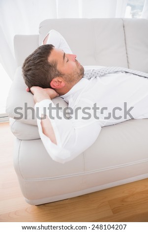 A businessman lying in the sofa hands crossed