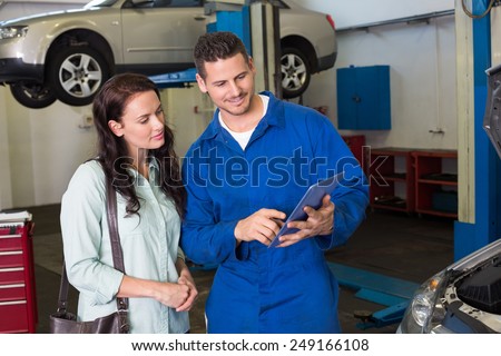 Mechanic showing tablet pc to customer at the repair garage