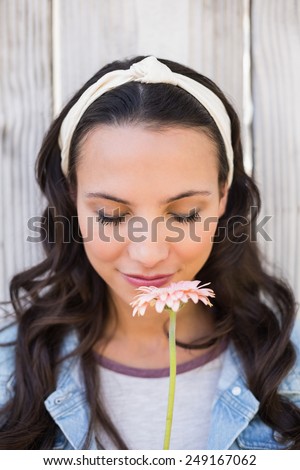 Pretty hipster smelling a flower against bleached wooden fence