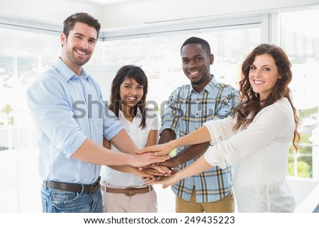 Happy coworkers joining hands in a circle in the office