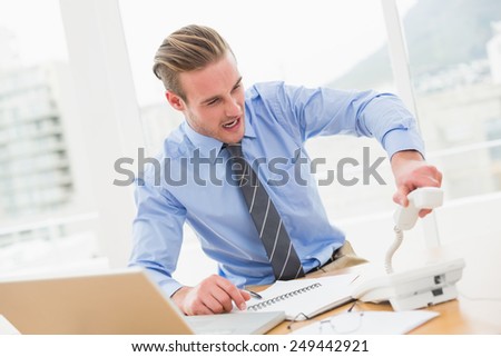 Angry businessman hanging up the phone in his office