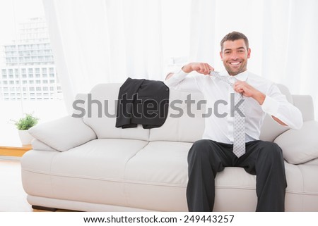 Businessman taking off his tie in his sofa