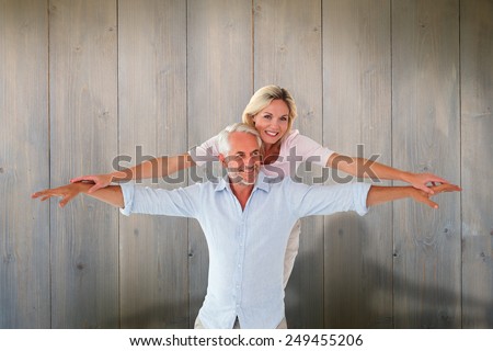 Smiling couple posing with arms out against pale grey wooden planks