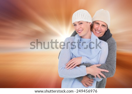 Casual couple in warm clothing against sunrise over field with tree