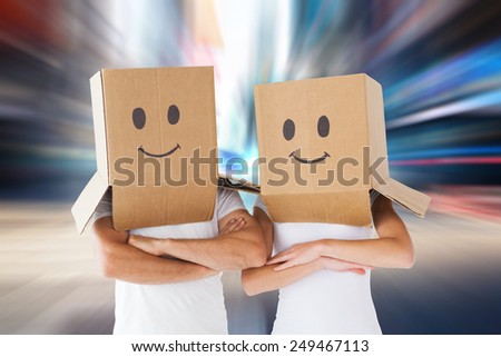 Couple wearing smiley face boxes on their heads against blurry new york street