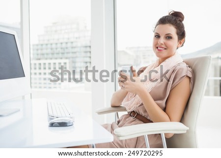 Relaxed businesswoman holding hot drink in the office