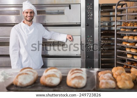 Happy baker leaning on professional oven at the bakery
