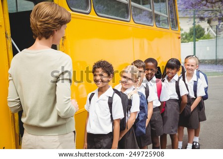 Cute schoolchildren waiting to get on school bus outside the elementary school
