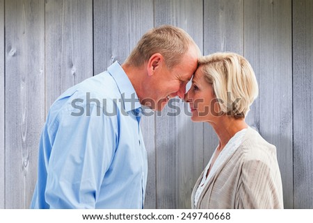 Happy mature couple facing each other against wooden planks