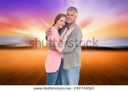 Casual couple hugging and smiling against countryside scene