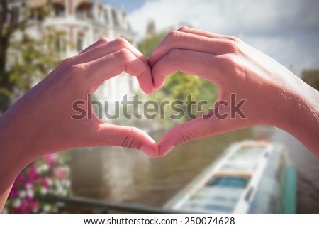 Hands making heart shape on the beach against canal in amsterdam
