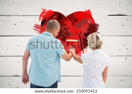 Happy older couple painting white wall against white wood