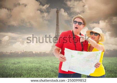 Happy tourist couple using map against paris under cloudy sky