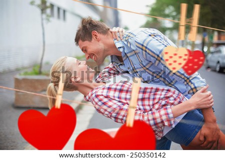 Hip romantic couple dancing in the street against hearts hanging on the line