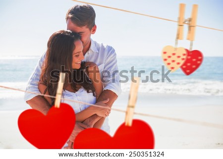 Loving couple cuddling against hearts hanging on the line