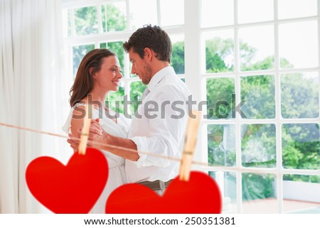 Loving young couple holding hands against hearts hanging on a line