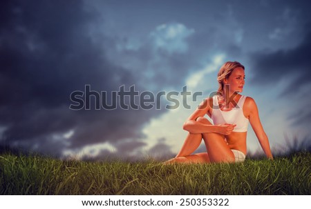 Gorgeous fit blonde in seated yoga pose against blue sky over grass