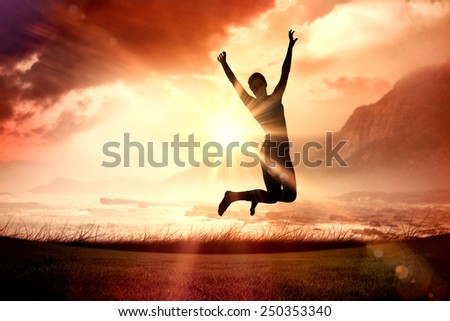 Sporty blonde jumping with arms out against sunrise over magical sea