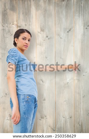Pretty brunette giving thumbs down against bleached wooden planks background