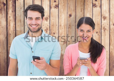 Happy couple sending text messages against wooden planks