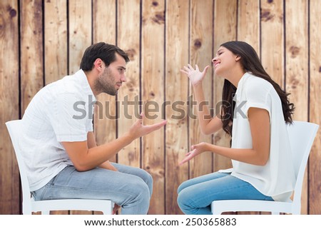 Couple sitting on chairs arguing against wooden planks