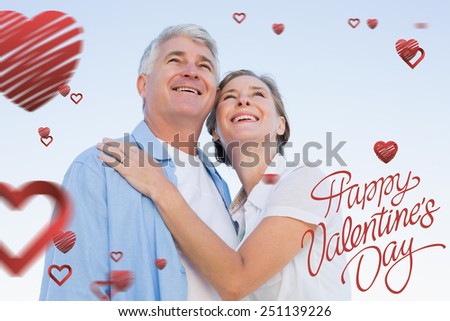Happy casual couple embracing under blue sky against happy valentines day